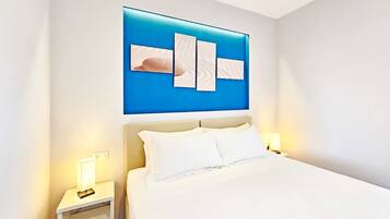 Una habitación de hotel con una cama, dos mesitas de noche y una obra de arte colgada en la pared.