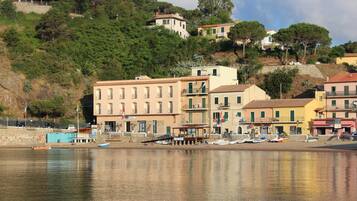 Stunning coastal town with residential and commercial buildings perched on a hillside, surrounded by lush greenery and a serene body of water.