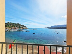 A coastal view with clear blue water, boats, and buildings on a hillside. - Hotel L'Approdo (Porto Azzurro)
