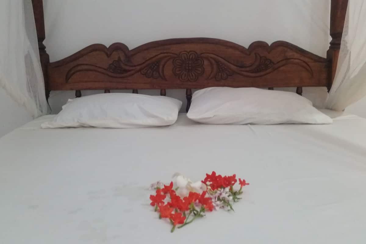 Uma cama com cabeceira de madeira e almofadas brancas.