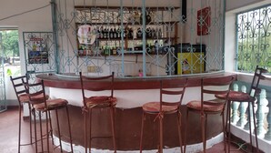 A bar area with a counter, bar stools, and a variety of bottles behind a metal railing. - St. Gotthard Motel Bar & Restaurant (Malindi)
