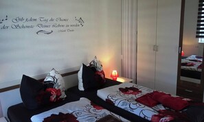 A hotel room with two beds, a red lamp, and a wall with a quote. - Vacation apartment 2 - Ück - Rolletschke Andreas (Ückeritz)