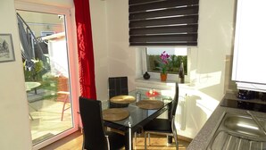 A modern kitchen with a glass dining table, black chairs, and a red curtain. - Vacation apartment 2 - Ück - Rolletschke Andreas (Ückeritz)