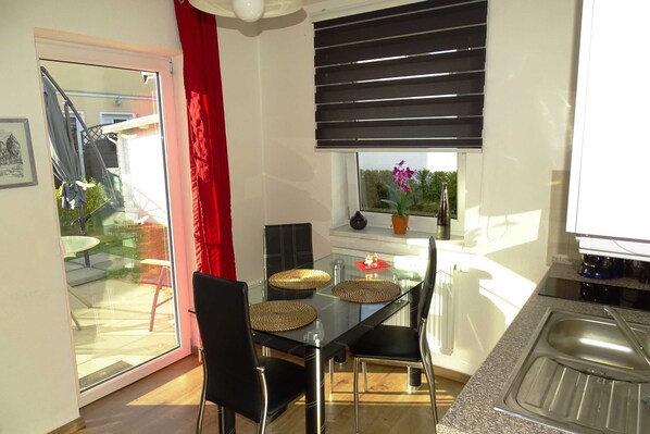 A modern kitchen with a glass dining table, black chairs, and a red curtain. - Vacation apartment 2 - Ück - Rolletschke Andreas (Ückeritz)