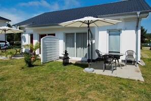 A single-story house with a patio area featuring outdoor furniture and a large umbrella. - Vacation apartment 2 - Ück - Rolletschke Andreas (Ückeritz)