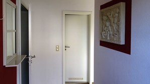 A hallway with a white door, a partially open window, and a wall-mounted sculpture. - Vacation apartment 2 - Ück - Rolletschke Andreas (Ückeritz)