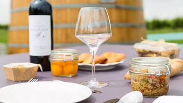 Uma mesa com uma garrafa de vinho, uma taça, potes de comida e um prato.