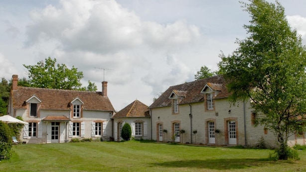 Une maison à deux étages avec une cour verdoyante et un grand arbre.