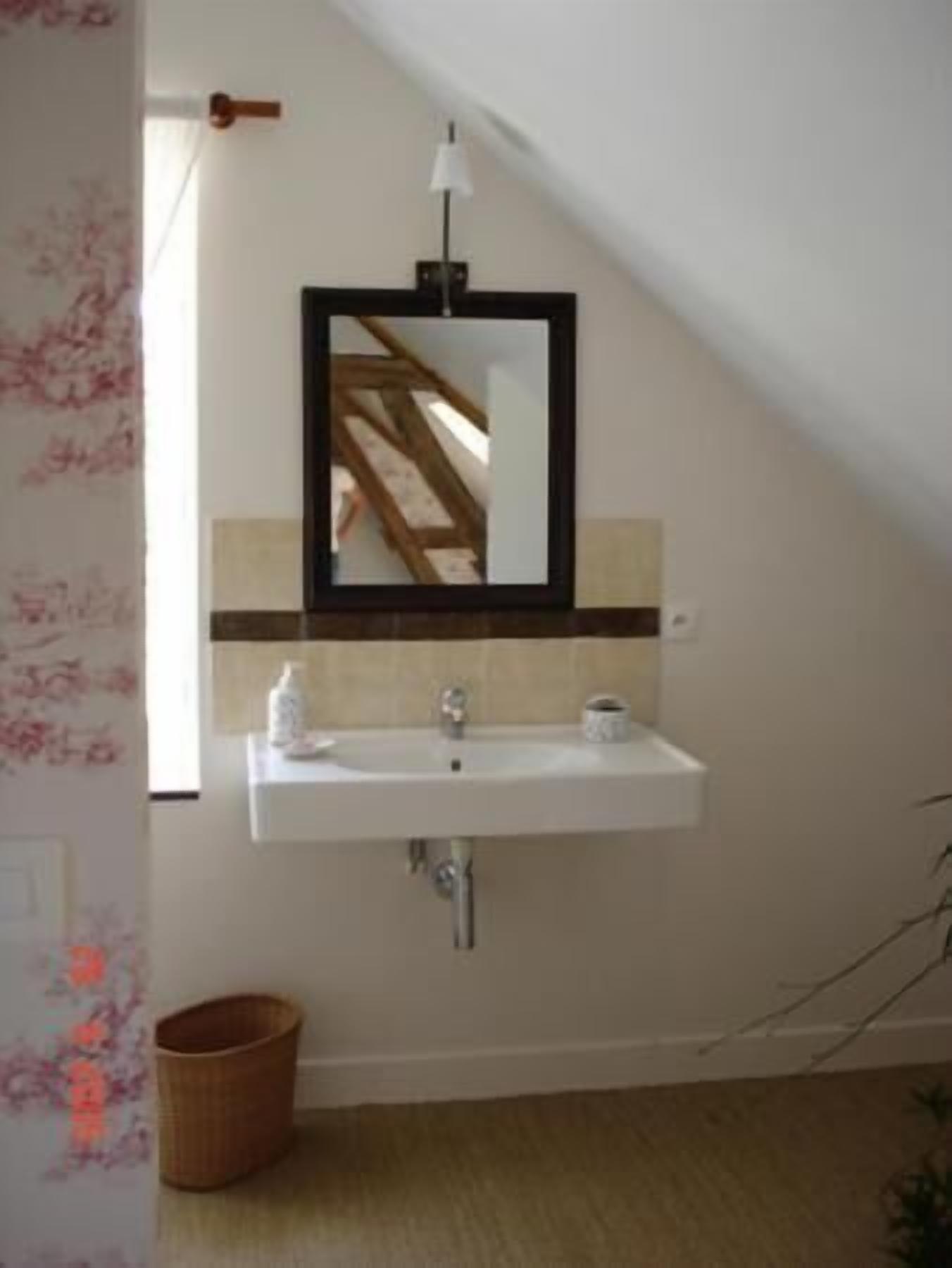 A bathroom with a white sink, a mirror, and a wooden floor.