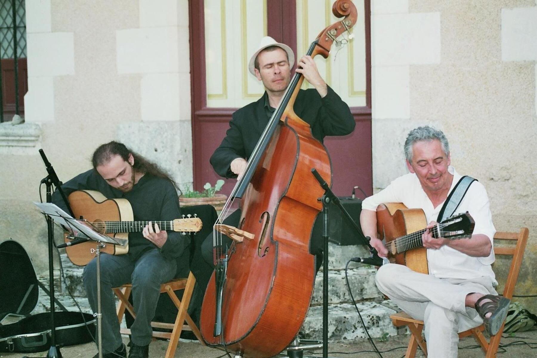 Tres músicos actuando al aire libre con instrumentos musicales.