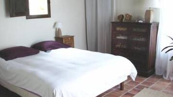 Un dormitorio con cama, cómoda, mesita de noche y ventana con cortinas.