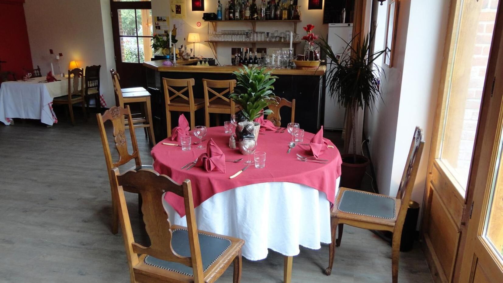 Zona pranzo con tavolo rotondo apparecchiato per quattro, circondato da sedie in legno.