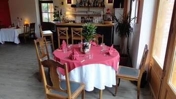 Zona pranzo con tavolo rotondo apparecchiato per quattro, circondato da sedie in legno.
