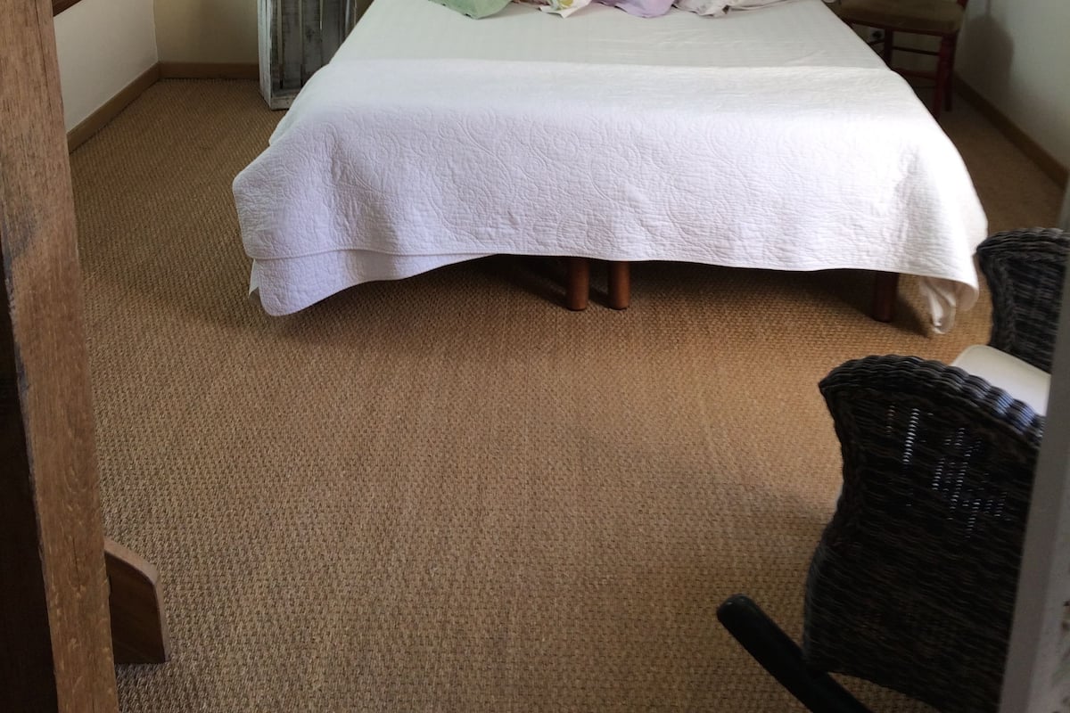 A bedroom with a bed, a chair, and a radiator.