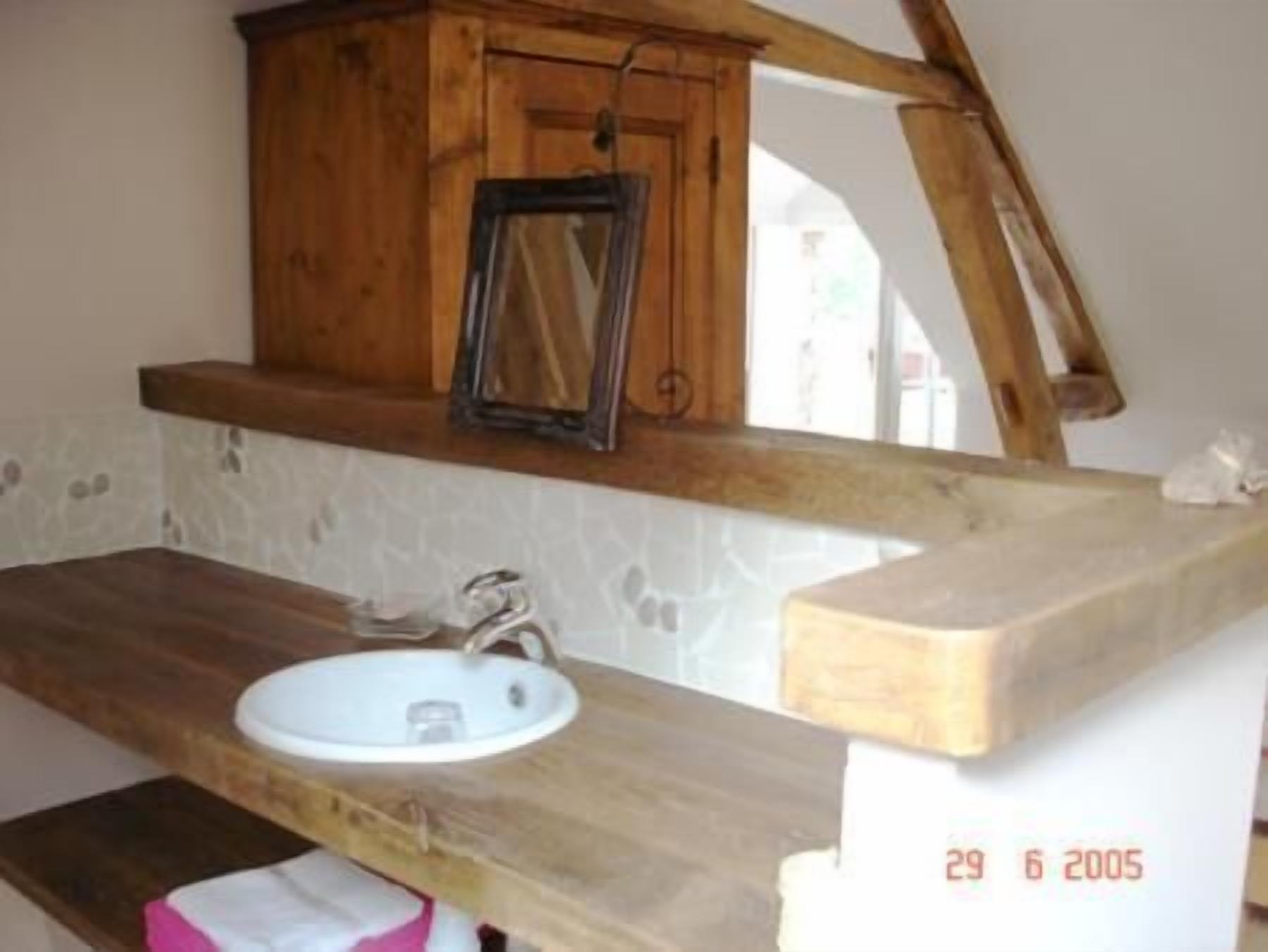 A rustic bathroom with a wooden vanity, a white sink, and a mirror.