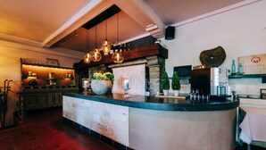 A kitchen with a central island, hanging pendant lights, and a stone fireplace. - De Kalvaar Hotel (Ninove)