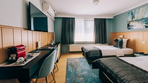 A hotel room with a bed, a desk with a computer, a chair, a coffee machine, and a painting on the wall. - De Kalvaar Hotel (Ninove)