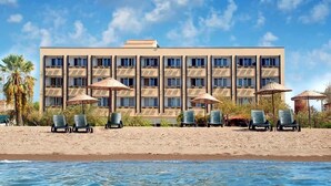 A hotel with a modern design, featuring multiple balconies, a pool area with lounge chairs, and umbrellas. - Dikili Sunset Club (Dikili)