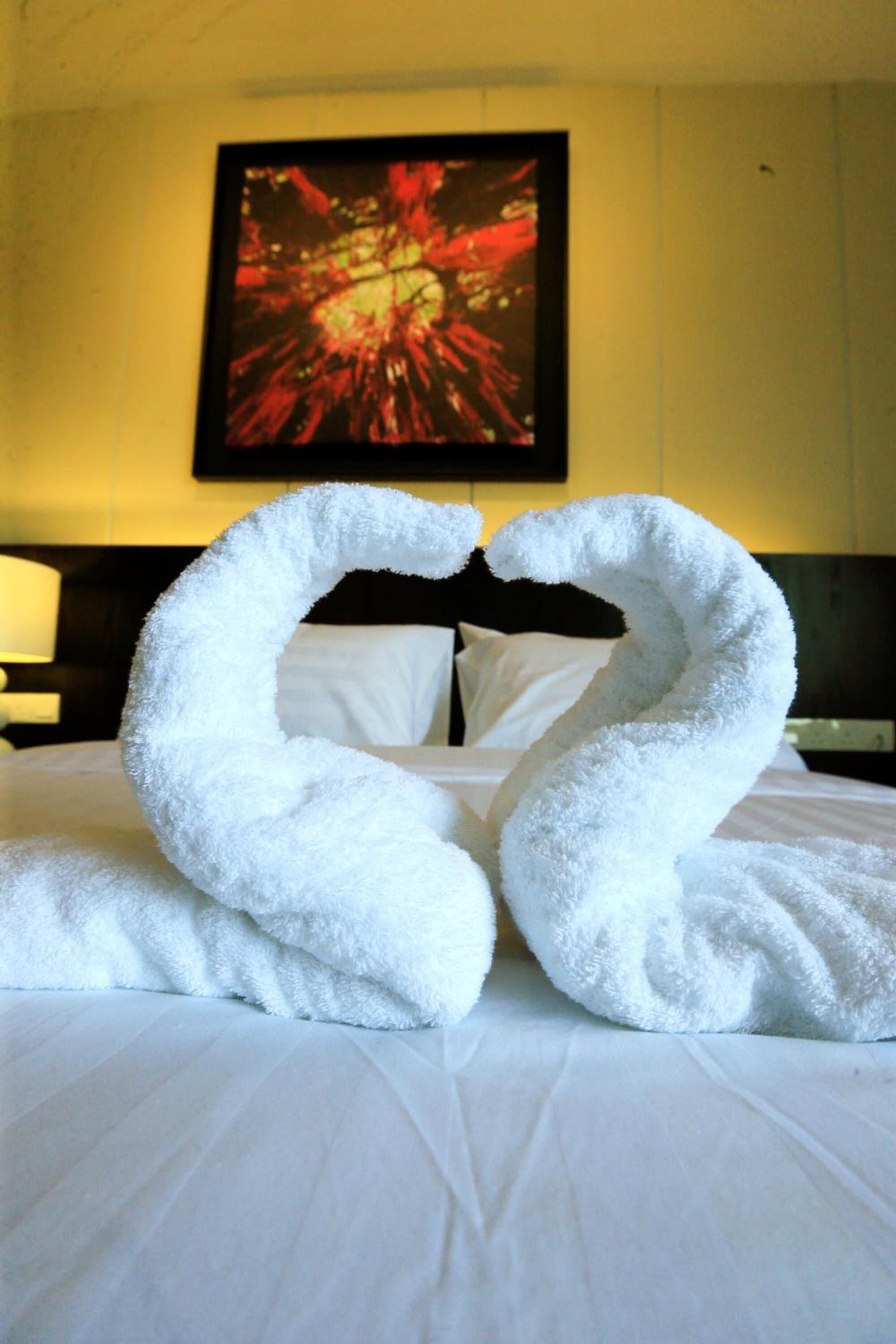 Una cama con dos grandes cisnes blancos hechos de toallas.