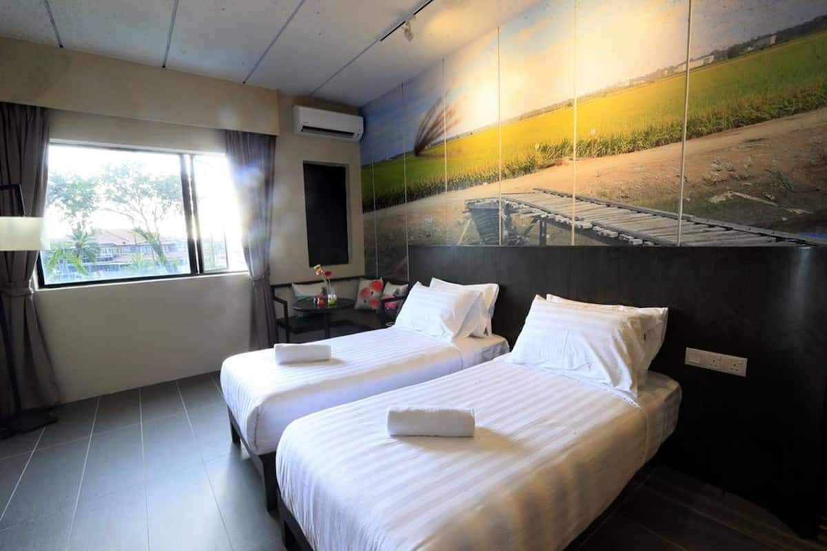 A hotel room with two beds, a window, a painting on the wall, and an air conditioning unit.