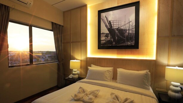Quarto de hotel com uma cama grande, um quadro na parede e vista pela janela.