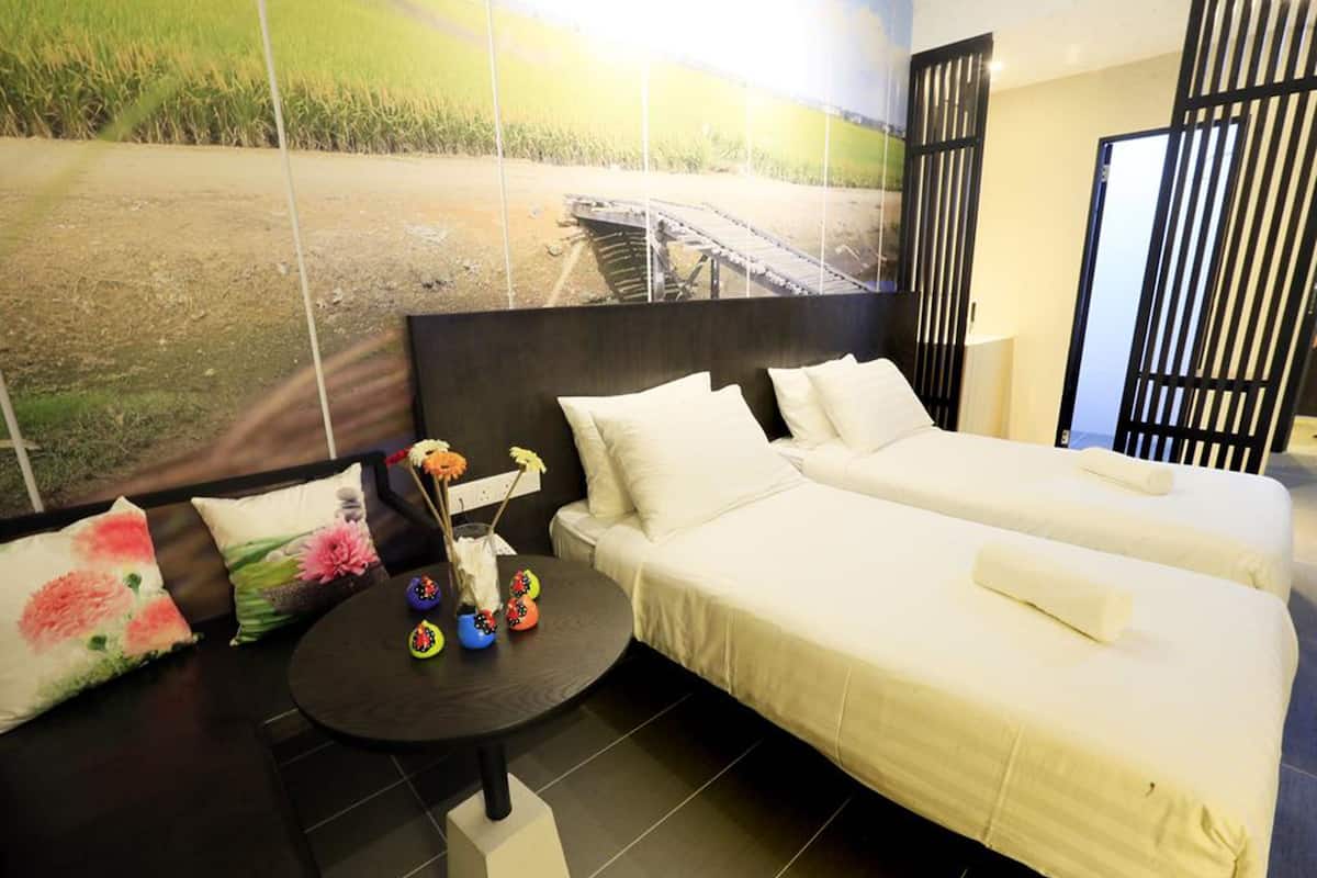 A hotel room with two beds, a small round table with decorative items, and a large window with a view of a bridge and fields.
