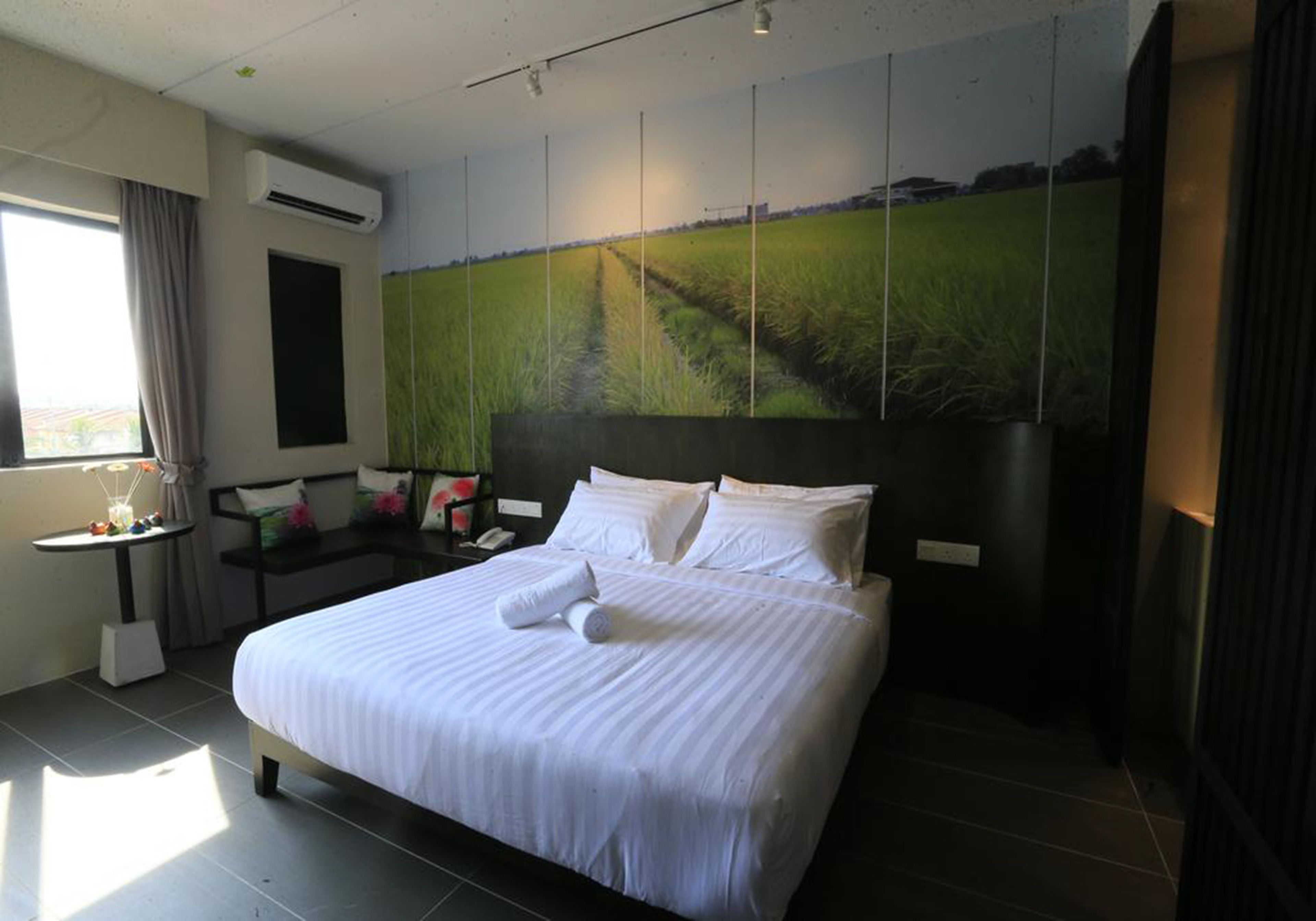 Habitación de hotel con una cama grande, un escritorio, una silla y una ventana con cortinas.