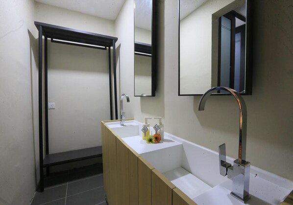 Un baño moderno con tocador de madera, dos lavamanos y un espejo grande.