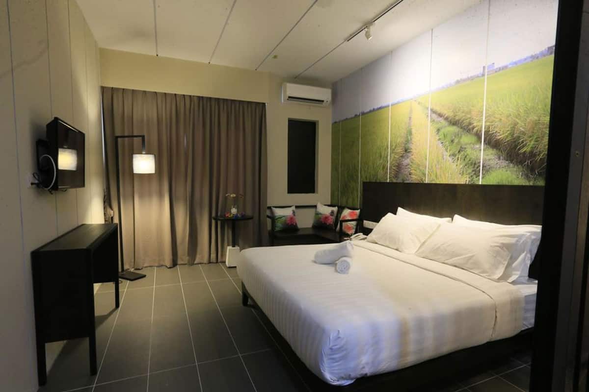 A hotel room with a bed, a desk, a chair, a lamp, and a large window with a view of a field.
