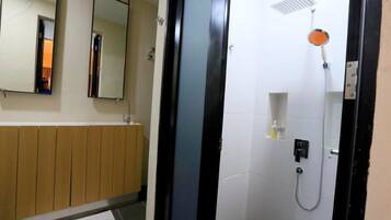 Un baño con ducha, espejo y toallero.