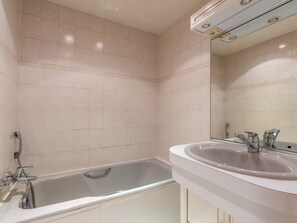 Une salle de bain avec une baignoire, un lavabo et un miroir.