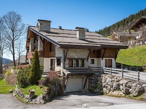 A stone building with a sloped roof, a wooden porch, and a garage.