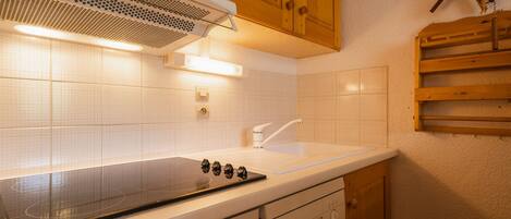 Una cocina con azulejos blancos, lavavajillas Bosch, armarios de madera y estufa integrada.