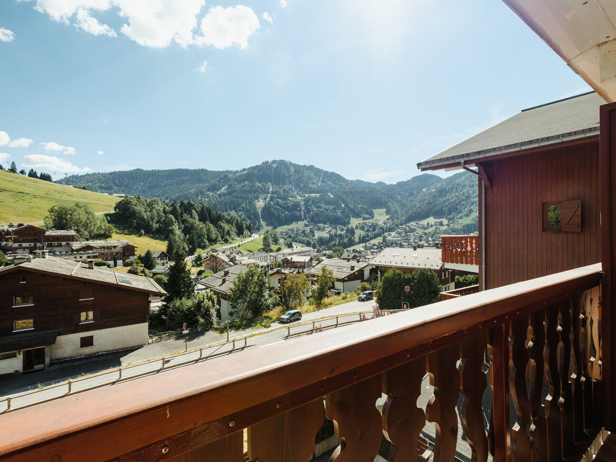 A balcony with a view of a village, mountains, and a road.