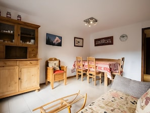 Quarto com armário de madeira, mesa de jantar com cadeiras, sofá e luminária no teto.