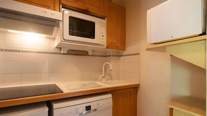 A compact kitchen with a microwave, dishwasher, and wooden cabinets.