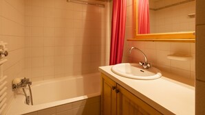 A bathroom with a bathtub, a sink, and a mirror.