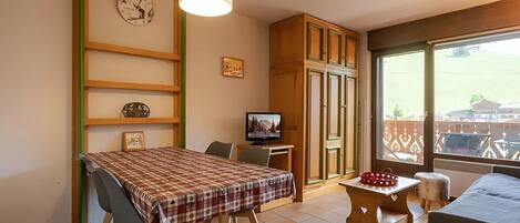 Un comedor con una mesa dispuesta para dos, un televisor y vistas al exterior.