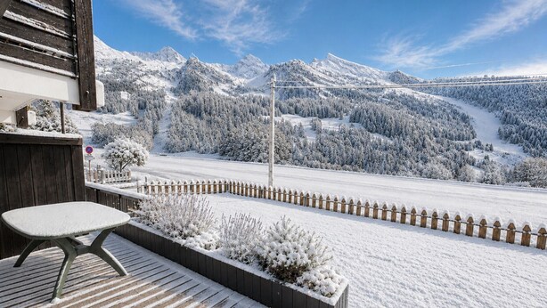 Ein mit Schnee bedeckter Balkon mit Blick auf eine Berglandschaft.