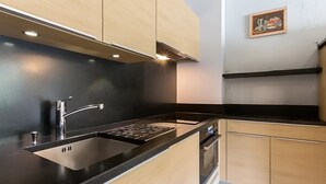 Eine moderne Küche mit schwarzer Arbeitsplatte, Spüle aus Edelstahl und Holzschränken.