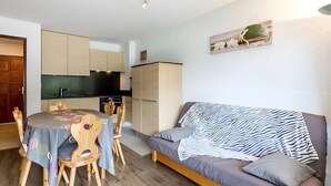 Ein kompakter Wohnbereich mit Essbereich, Küchenzeile und einer Couch.