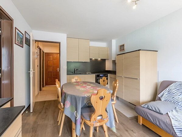 Un espacio habitable compacto con una mesa de comedor, sillas, kitchenette, sofá y armario.
