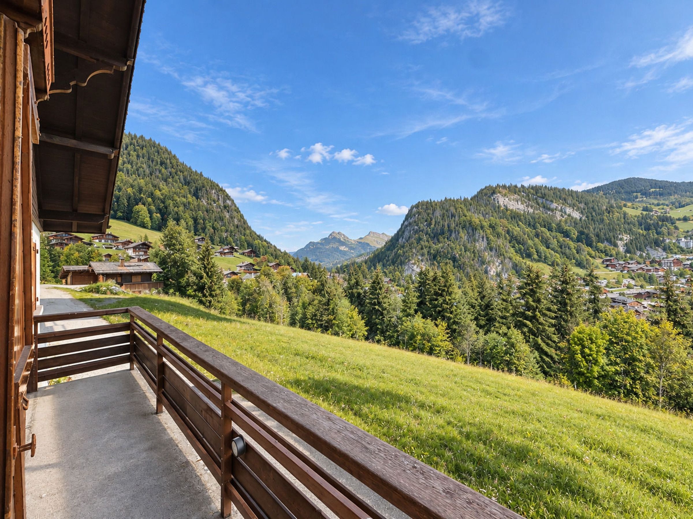 Un balcón de madera con vistas a un paisaje montañoso, casas y cielo despejado.