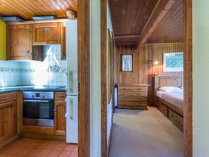 A compact kitchen with wooden cabinets, a stove, and a refrigerator. - Chalet near slopes, fireplace, pets allowed, garage, WIFI (La Clusaz)