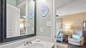A bathroom with a large mirror, a sink, and two starfish wall decorations. - Come Stay At This Cozy Beach Condo! (Gulf Shores)