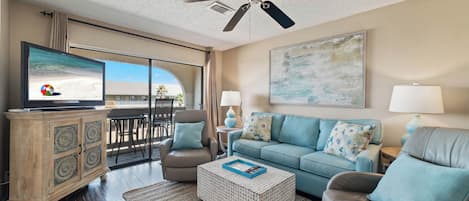 A spacious living room with a television, a ceiling fan, a sofa, a coffee table, and a cabinet.