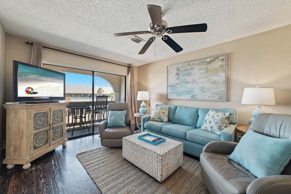 A spacious living room with a television, a ceiling fan, a sofa, a coffee table, and a cabinet.