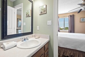 A bathroom with a large mirror, a sink, and a vanity with drawers.