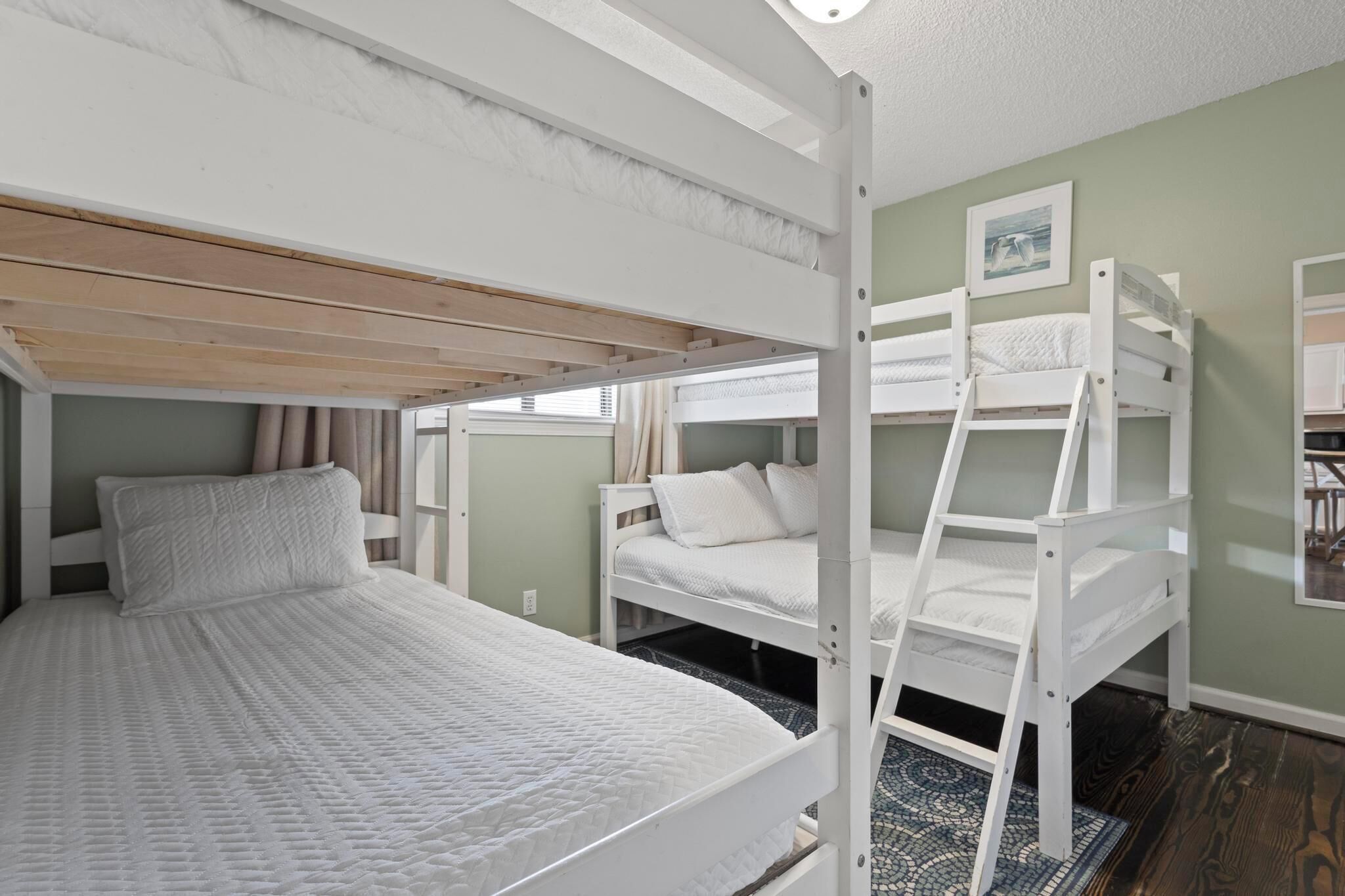 A bunk bed room with a wooden ladder, a white mattress, and a framed picture on the wall.