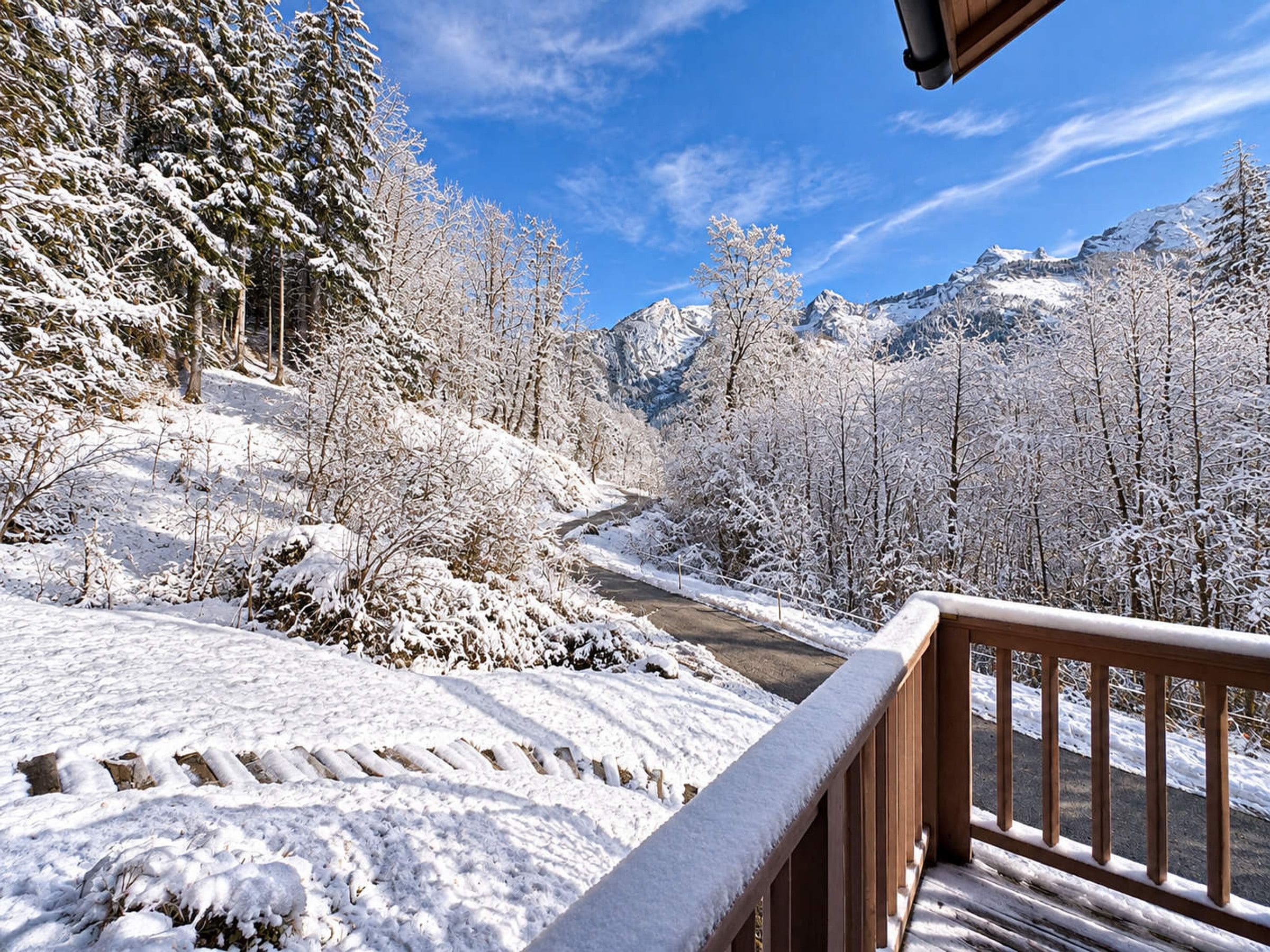 A snow-covered landscape with a wooden deck and a mountain view.